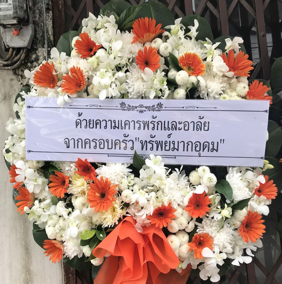 พวงหรีดดอกไม้สดทรงกลมโทนเขียวขาว แต่งขอบรอบพวงหรีดด้วยใบไม้สดอย่างสวยงาม